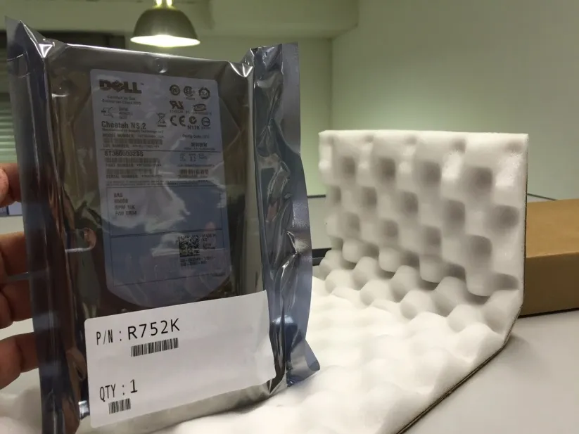 A drive sealed in an anti-static bag with a part number and quantity label, held above foam packing