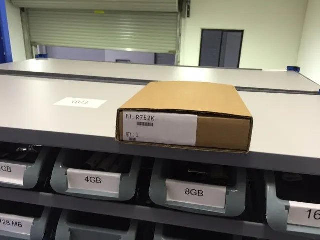 A labelled box packed on a bench above binned components